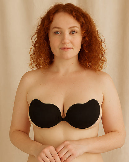 Woman wearing a black strapless bra against a beige background